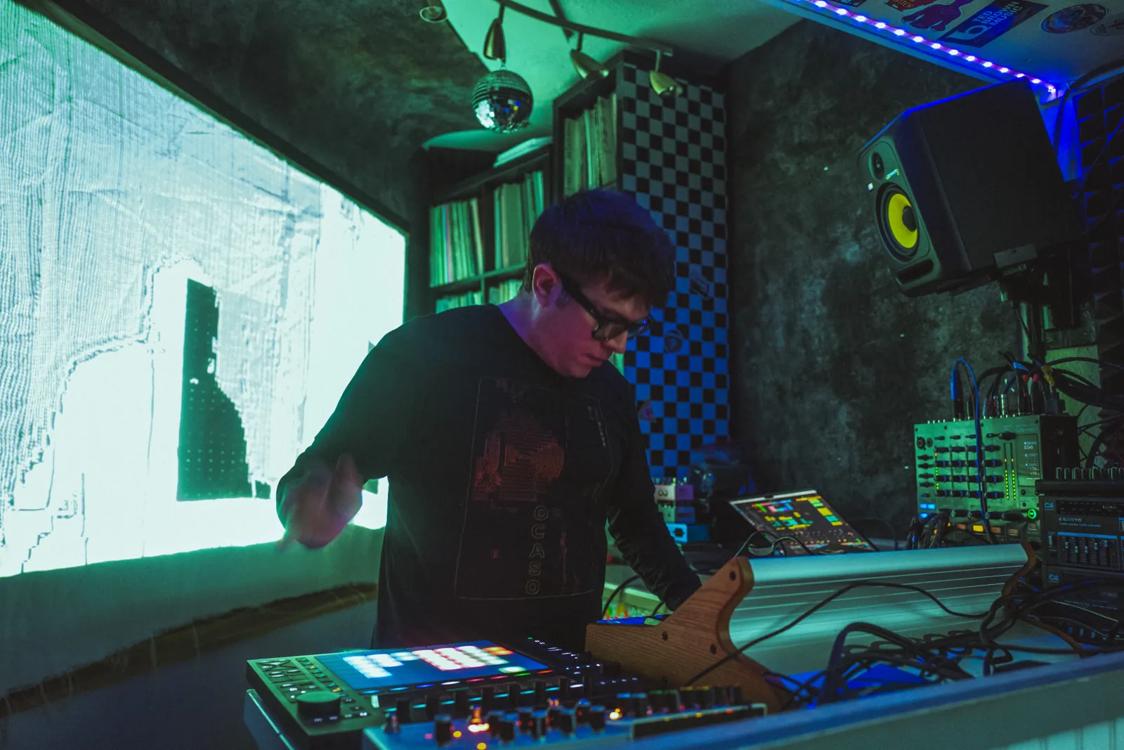 Nil Elses playing electronic instruments in front of a projection