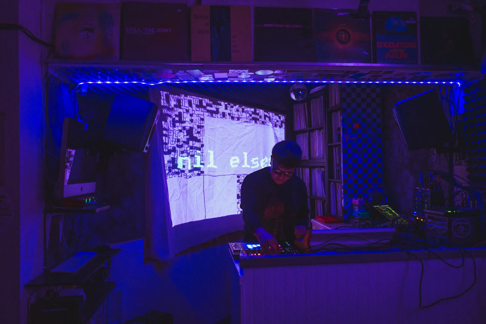 Nil Elses performing in a room filled with blue and violet light