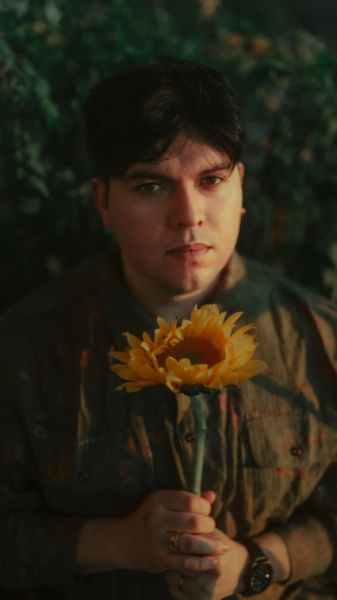 Nil Elses holding a sunflower in warm studio light